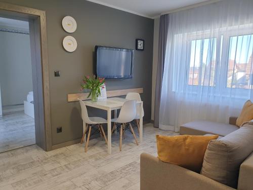 a living room with a table and chairs and a tv at Pokoje Sandra I in Łeba