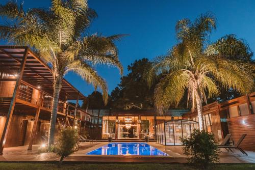 a house with a swimming pool and palm trees at Puerto Dijama Hotel Boutique in Carmelo