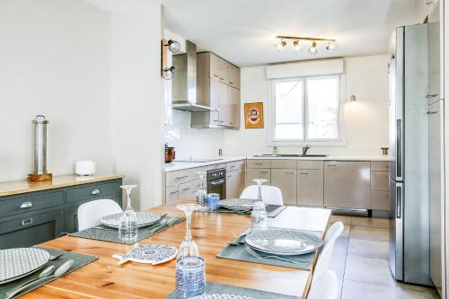 une cuisine avec une table avec des chaises et un réfrigérateur dans l'établissement L'Atoll Wifi Jardin Parking, à Beaucouzé