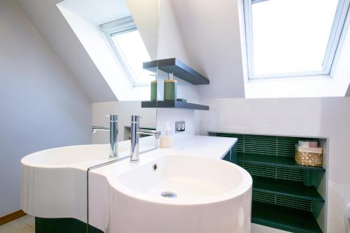 une salle de bain avec un lavabo blanc et une fenêtre dans l'établissement L'Atoll Wifi Jardin Parking, à Beaucouzé