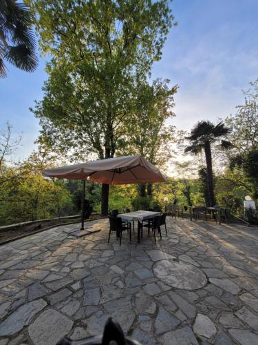 a table and chairs with an umbrella on a stone patio at BB60 in Asti