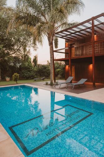 a swimming pool with two chairs and a house at Puerto Dijama Hotel Boutique in Carmelo
