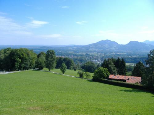 a field of green grass with a house in the distance at Berggasthaus Kraxenberger in Brannenburg