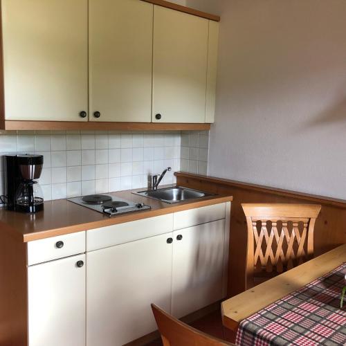 a kitchen with white cabinets and a sink and a table at Gästehaus Tanneck in Reit im Winkl