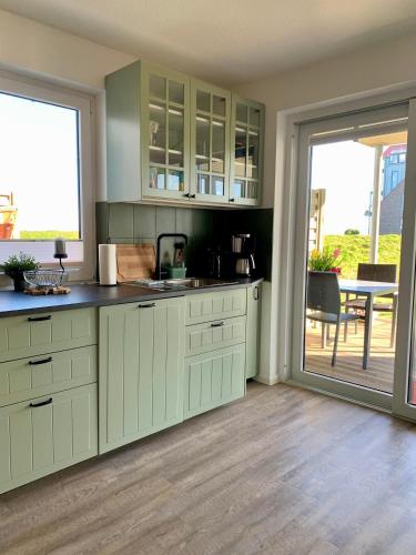 a kitchen with green cabinets and a sliding glass door at Direkt am Meer in Fehmarn