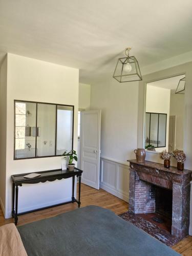 a living room with a fireplace and a mirror at La Maison Pelloquin in Bernières-sur-Mer