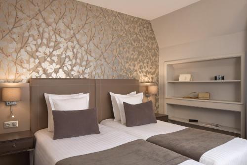 a bedroom with two beds and a floral wall at Timhotel Opéra Blanche Fontaine in Paris
