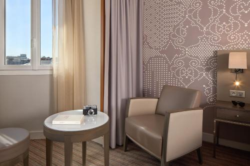a room with a chair and a table and a window at Timhotel Opéra Blanche Fontaine in Paris