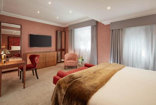 a hotel room with a large bed and a desk at Flemings Mayfair - Small Luxury Hotel of the World in London