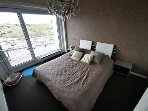 ein Schlafzimmer mit einem Bett und einem großen Fenster in der Unterkunft Appartement 1 chambre Twenty One Vue imprenable sur la mer in Koksijde