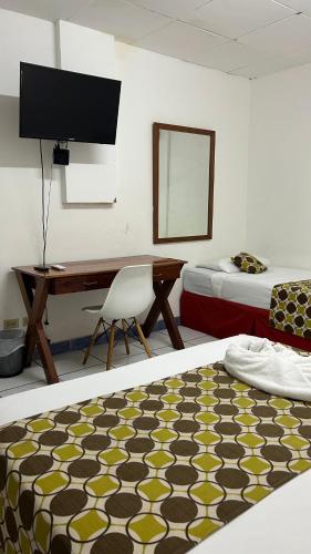 a room with two beds and a desk with a computer at La Posadita de Bolonia in Managua