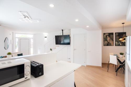 a white kitchen with a microwave and a table at Casa Jasmine Family Villa near the beach in Barcelona