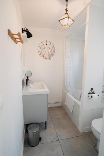 a bathroom with a sink and a tub and a toilet at La Maison Pelloquin in Bernières-sur-Mer