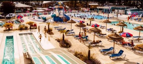 une grande piscine avec un parc aquatique avec des personnes et des parasols dans l'établissement Les Dunes de Contis 4 étoiles emplacement 459 3CH 1SDB 8 pers, à Saint-Julien-en-Born