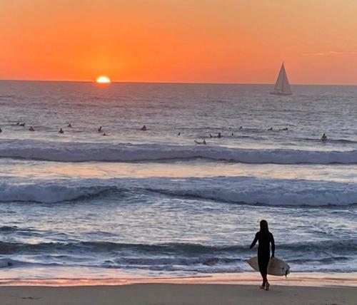 une personne se promenant sur la plage avec une planche de surf dans l'établissement Appartement à 200 m de l'océan de Capbreton, à Capbreton