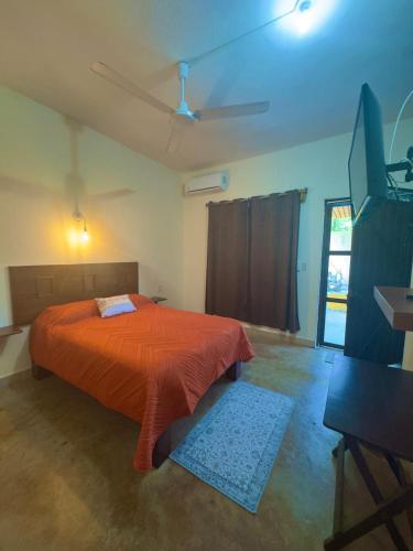 a bedroom with a bed with an orange comforter and a ceiling at Casa Majagua in Brisas de Zicatela