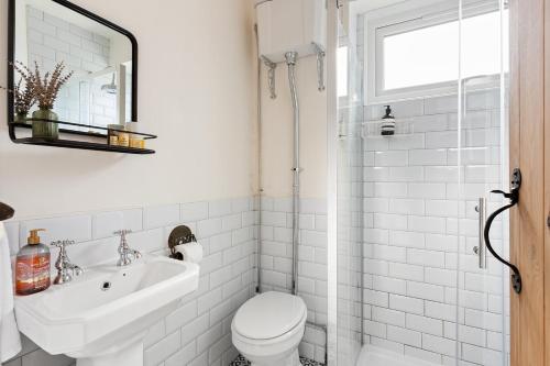 a white bathroom with a toilet and a sink at Stylish cottage with balcony near seafront in Falmouth