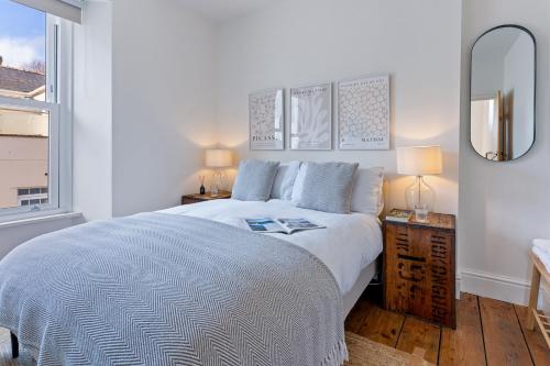 a white bedroom with a large bed and a window at Stylish cottage, log burner - Tregavone Cottage in Falmouth