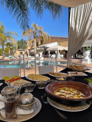 a table topped with plates of food on a table near a pool at Weedan Hôtel&Spa Marrakech in Oulad Snaguia