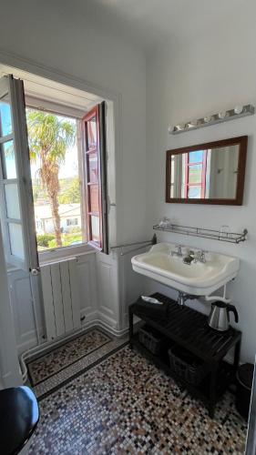 une salle de bain blanche avec un lavabo et une fenêtre dans l'établissement Erlande Baïta, à Urrugne