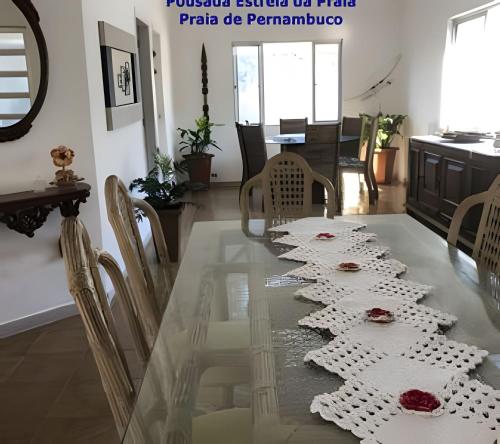 a dining room with a glass table with roses on it at Pousada Estrela da Praia - Aluguel Casa in Guarujá