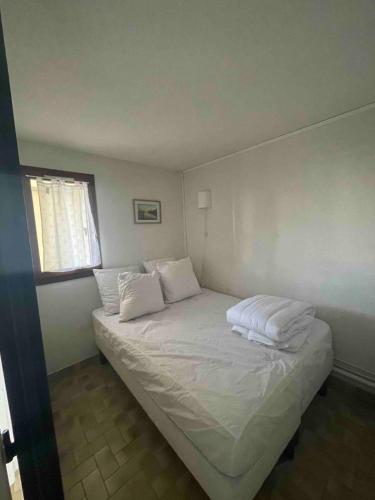 une chambre avec un lit avec des draps blancs et des oreillers dans l'établissement Chez Maéva, au Cap d'Agde