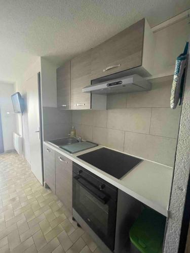 une cuisine avec un évier et une cuisinière four supérieur dans l'établissement Chez Maéva, au Cap d'Agde