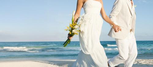 a bride and groom walking on the beach at InterContinental Halong Bay Resort by IHG in Ha Long