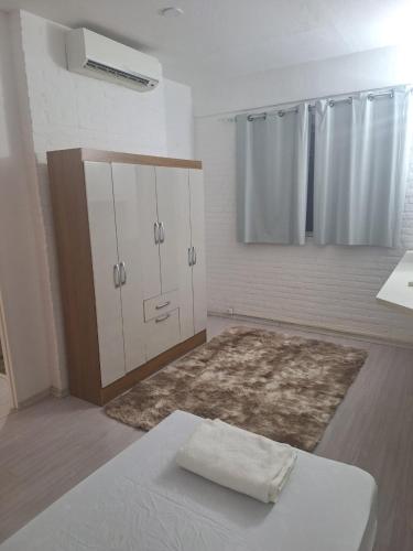a white room with a bed and a cabinet and a rug at Domus Hotel Campinas in Campinas