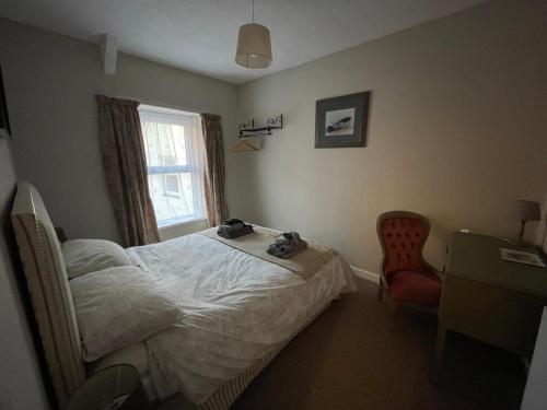 a bedroom with a bed and a chair and a window at 3 Stable Mews in Holsworthy