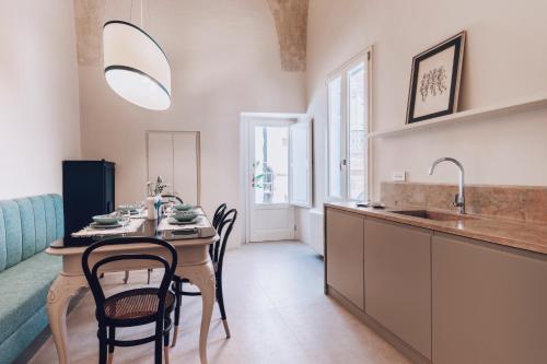 Una cocina con una mesa con sillas y un fregadero. en Casa Annabella - Palazzo Venneri Lloyd, en Gallipoli