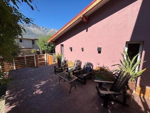 a patio with chairs and tables next to a pink building at Cabañas Sublime Bolson in El Bolsón