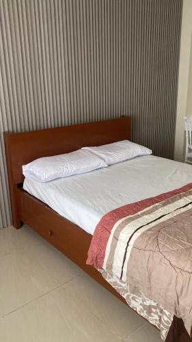 a bed with white sheets and a wooden head board at CitySouth Premier Inn in Bulatok