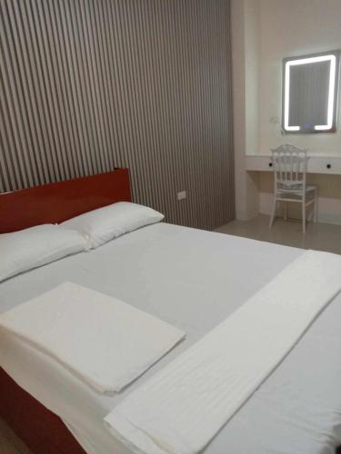 a bedroom with a white bed with a window and a chair at CitySouth Premier Inn in Bulatok