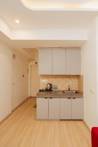 an empty kitchen with white cabinets and a wooden floor at Skystay Lucknow in Lucknow