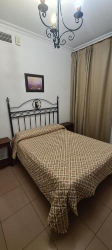 a bedroom with a bed and a chandelier at Hostal Trajano in Seville