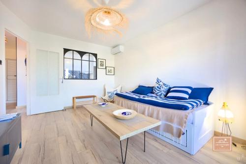 - un salon avec un lit bleu et une table dans l'établissement La Mandriote, plage à pied et clim, à Saint-Mandrier-sur-Mer
