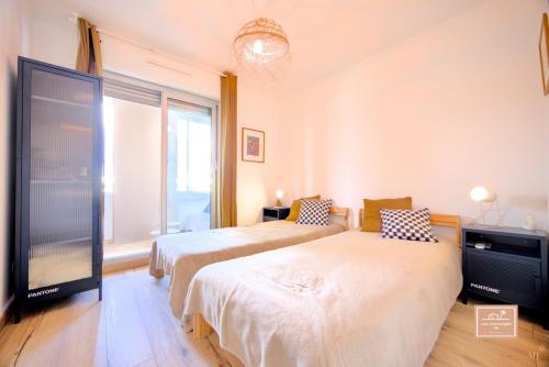 une chambre avec deux lits et une grande fenêtre dans l'établissement La Mandriote, plage à pied et clim, à Saint-Mandrier-sur-Mer