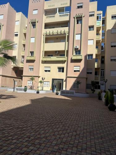 a large building with a brick courtyard in front of it at Appartement de lux avec piscine in Mohammedia