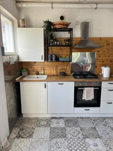 a kitchen with white cabinets and a sink and a stove at Appartamento luce in Fanano