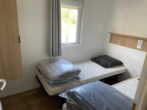 deux lits dans une petite pièce avec une fenêtre dans l'établissement Les Oyats 4 étoiles emplacement AJ17 2CH 2SDB 6 pers, à Seignosse