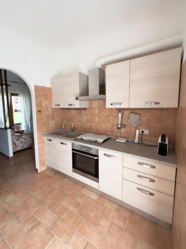 una cucina con armadietti bianchi e pavimento piastrellato di Residenza Lucia a Campagnano di Roma