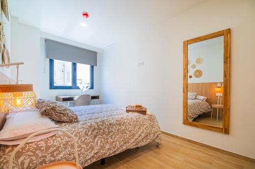 a bedroom with a bed and a mirror at CARTAGENAFLATS - San Diego Suites in Cartagena
