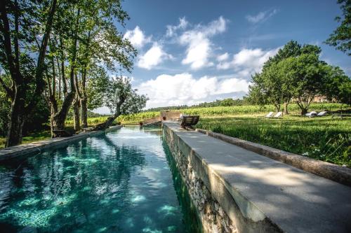 un canal avec de l'eau bleue dans un parc arboré dans l'établissement Château La Villatade, à Sallèles-Cabardès