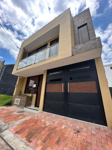 a house with black garage doors on a brick driveway at Apartamento Ubate in Ubaté
