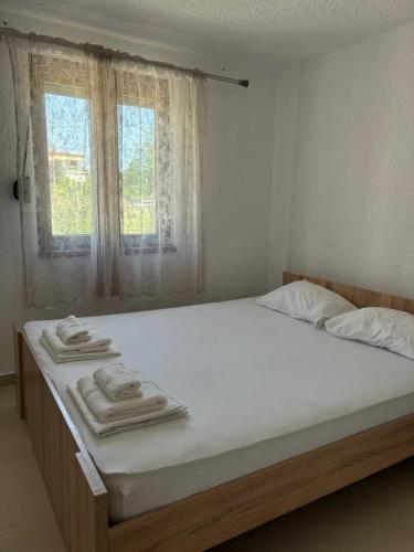 a bedroom with a bed with white sheets and a window at Garden Haven 100m from the Sea in Siviri