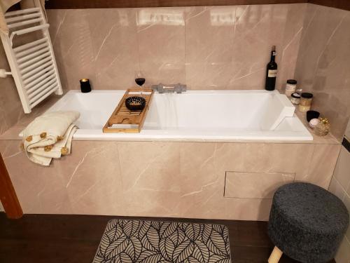 a bath tub with a bottle of wine and a chair at Villa Seychelles in Nieul-sur-Mer