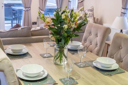 a table with plates and glasses and a vase of flowers at Vacant Nests Seton Sands The Kings Barns in Port Seton