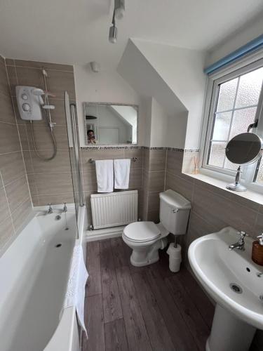 a bathroom with a tub and a toilet and a sink at Easter Cottage in Shaftesbury