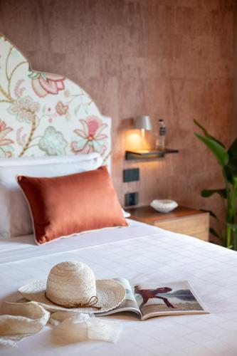 a hat and a book sitting on a bed at Antalia Boutique Hotel in Positano